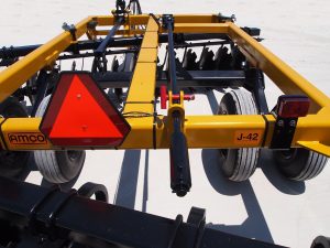 Closeup of J42 Wheel Offset Harrow hydraulic cylinder and safety emblem