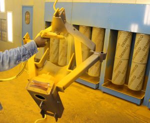 AMCO equipment part being powder-coated with yellow finish