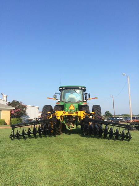 Terracing plow on green tractor with blue sky