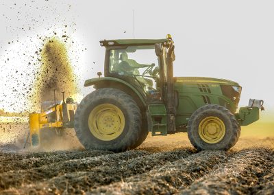 Side view of Dominator Vertical Rotary Ditcher in the field with green tractor