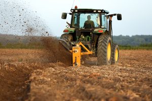 Full view of Dominator Vertical Rotary Ditcher in the field with tractor