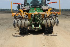 Full view of AMCO LJ6 Levee Plow being transported on the back of a green tractor