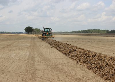Full view of AMCO LJ6 Levee Plow in the field with a tractor