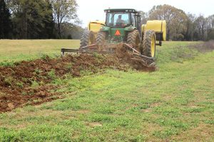 Full view of AMCO TJ3 Terracing Plow in field with green tractor