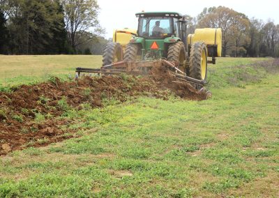 Full view of AMCO TJ3 Terracing Plow in field with green tractor