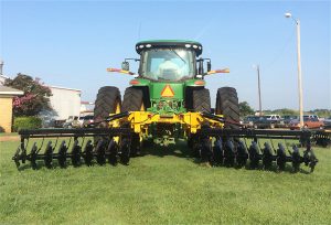 Full view of AMCO TJ3 Terracing Plow with green tractor on grass