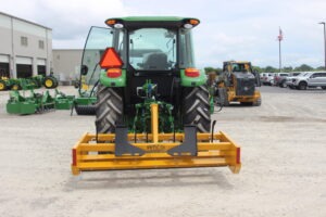 Back view of Z-7 with scarifiers installed on John Deere tractor on AMCO lot with other equipment in the background