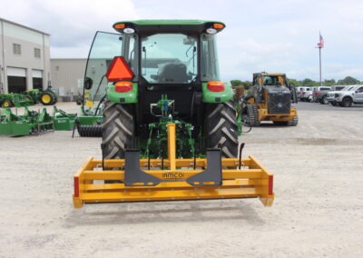 Back view of Z-7 with scarifiers installed on John Deere tractor on AMCO lot with other equipment in the background