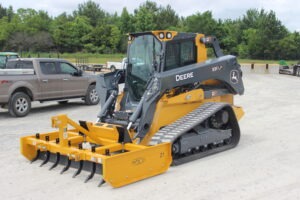 Z-7 with scarifiers installed on John Deere skid steer on AMCO lot with truck in background