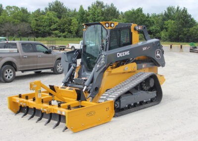 Z-7 with scarifiers installed on John Deere skid steer on AMCO lot with truck in background